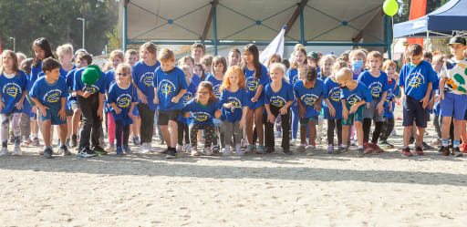 Students in blue Cottage Lake shirts lined up at the start of the Fun Run, Walk and Roll